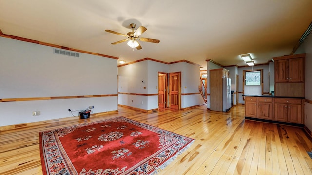 interior space featuring ornamental molding, visible vents, light wood finished floors, and a ceiling fan