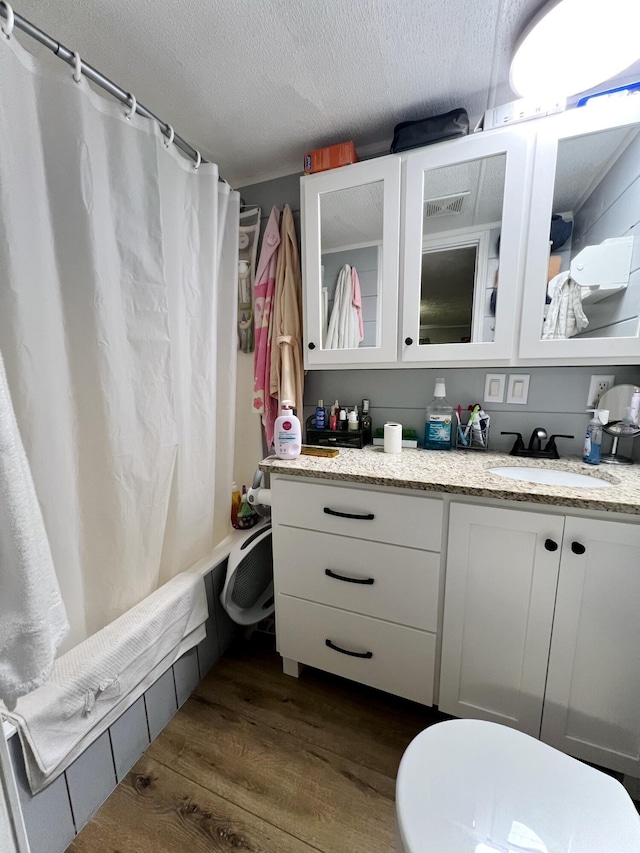 bathroom with shower / tub combo, vanity, a textured ceiling, and wood finished floors