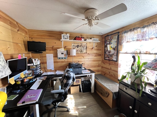 home office featuring ceiling fan, wooden walls, a textured ceiling, and wood finished floors