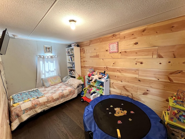 bedroom featuring a textured ceiling, wood walls, and wood finished floors