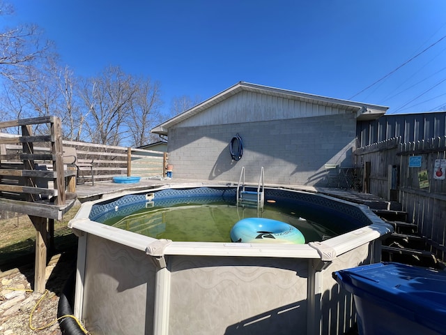 view of pool featuring fence, a wooden deck, and a hot tub