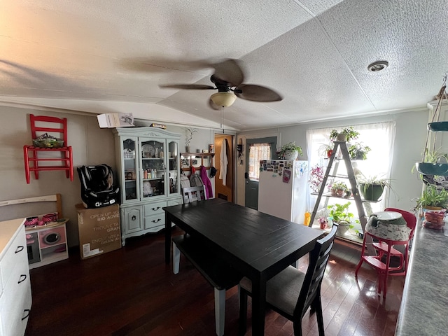 dining space with a textured ceiling, ceiling fan, dark wood-type flooring, and lofted ceiling