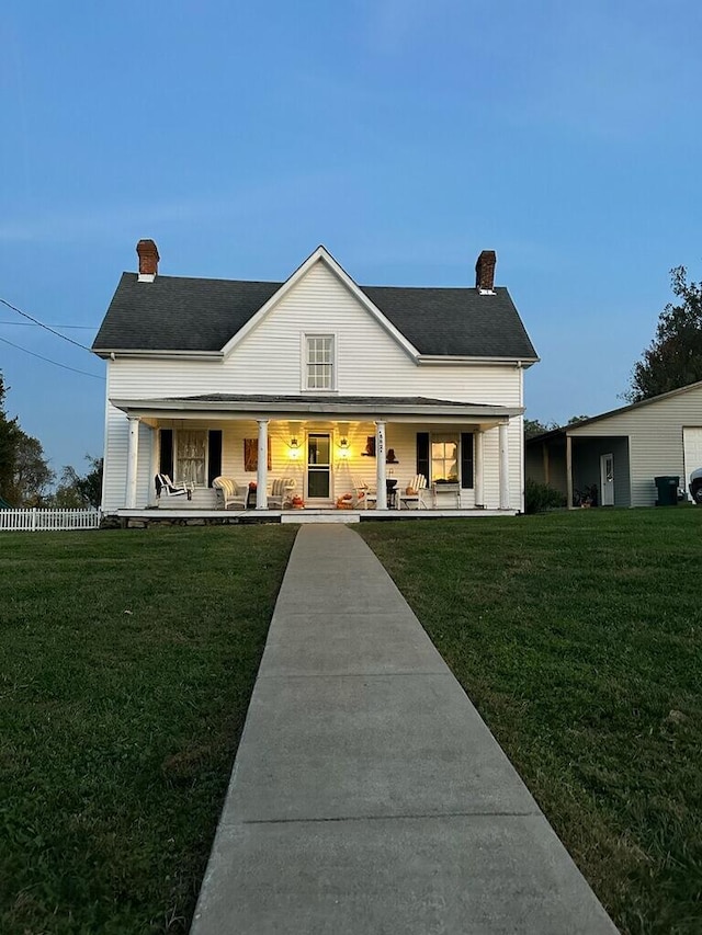 farmhouse inspired home with covered porch, fence, a chimney, and a front lawn