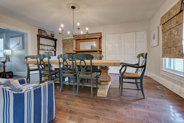 dining area with dark wood-style flooring, visible vents, a notable chandelier, and baseboards