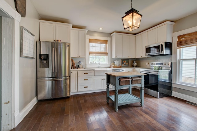 kitchen with dark wood-style floors, stainless steel appliances, light countertops, white cabinetry, and a sink