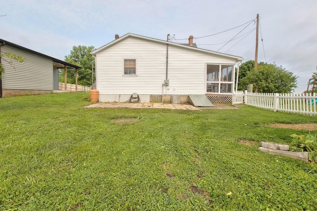 rear view of house featuring a sunroom, fence, and a lawn