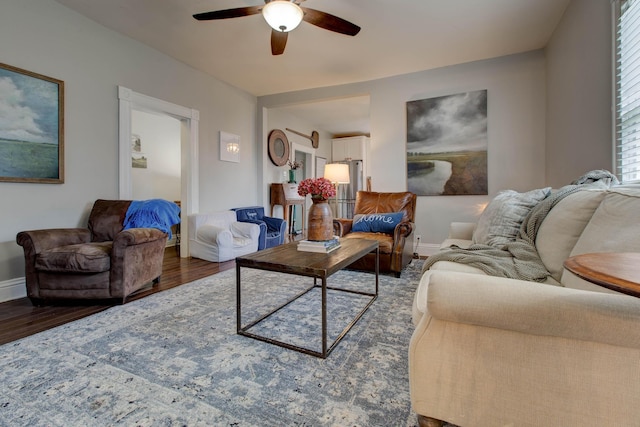 living room featuring wood finished floors, a ceiling fan, and baseboards