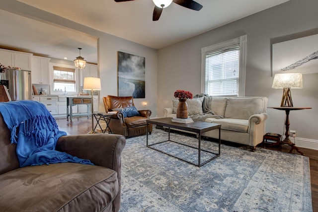 living area featuring wood finished floors, a ceiling fan, and baseboards