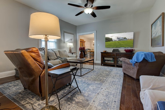 living room featuring a ceiling fan, baseboards, and wood finished floors