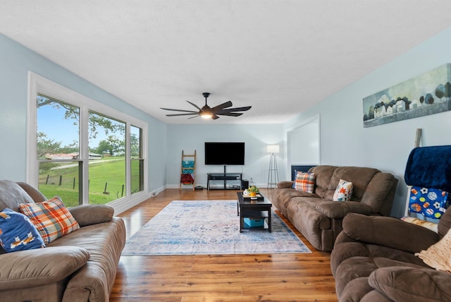 living room with baseboards, a ceiling fan, and wood finished floors