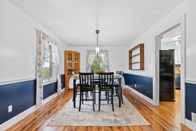 dining space featuring hardwood / wood-style flooring, baseboards, and a textured ceiling