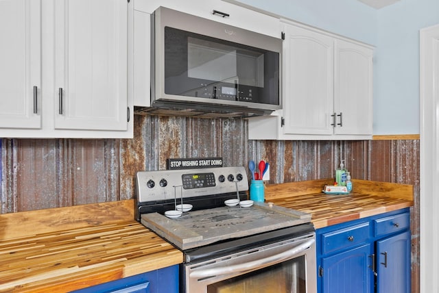 kitchen with appliances with stainless steel finishes, wood counters, and blue cabinetry