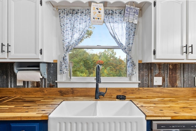 kitchen featuring butcher block countertops, white cabinets, a sink, and stainless steel dishwasher