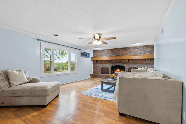 living area featuring crown molding, a fireplace, visible vents, light wood-style flooring, and a textured ceiling