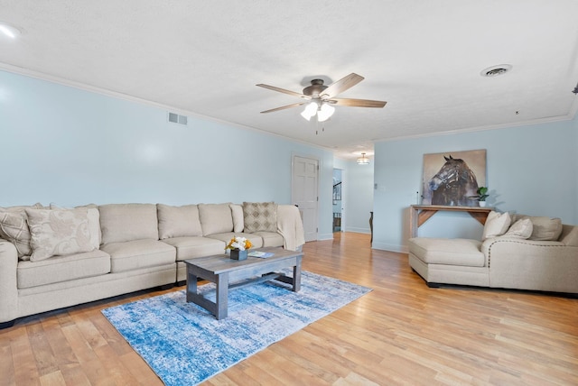 living area featuring light wood-type flooring, a ceiling fan, visible vents, and crown molding