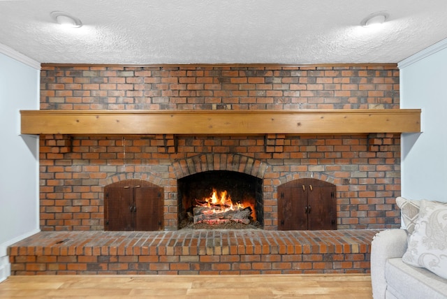 details with a brick fireplace, crown molding, a textured ceiling, and wood finished floors