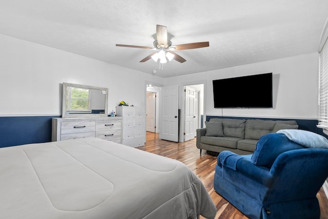 bedroom with light wood-type flooring, a textured ceiling, and a ceiling fan