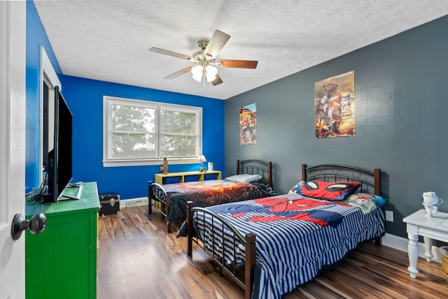 bedroom with a textured ceiling, baseboards, and wood finished floors