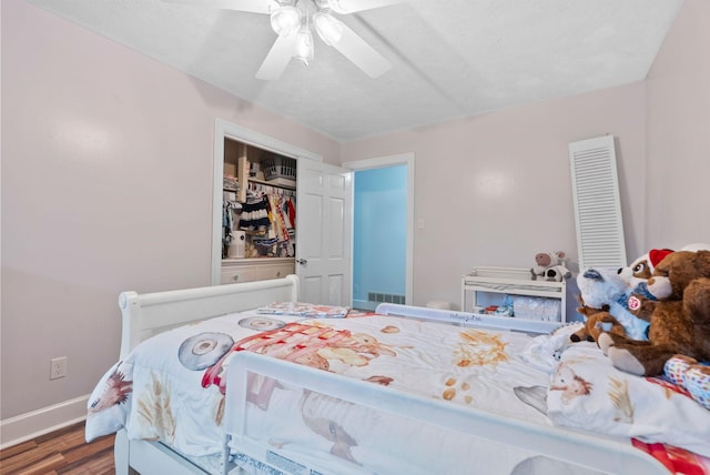 bedroom featuring ceiling fan, wood finished floors, visible vents, baseboards, and a closet