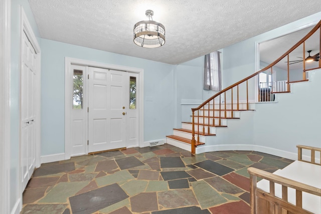 foyer with baseboards, visible vents, stairway, and stone tile flooring