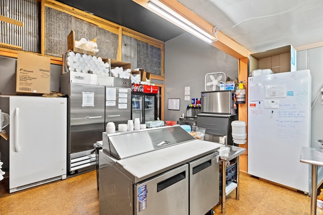 kitchen featuring light floors, stainless steel built in refrigerator, and freestanding refrigerator