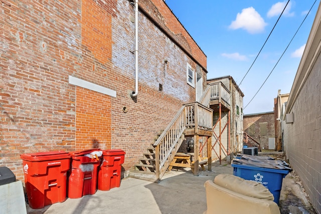 view of side of property with central AC, brick siding, and stairway