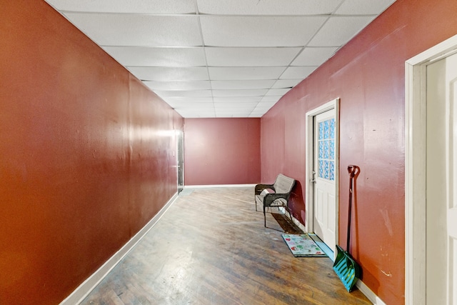 hall featuring a drop ceiling, baseboards, and wood finished floors