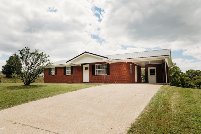 ranch-style home featuring driveway, brick siding, an attached carport, and a front yard