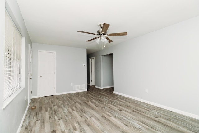 unfurnished room with visible vents, ceiling fan, baseboards, and wood finished floors