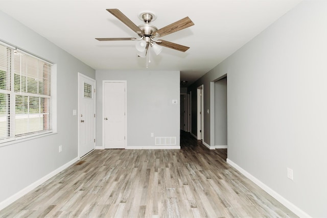 spare room featuring light wood finished floors, baseboards, visible vents, and a ceiling fan