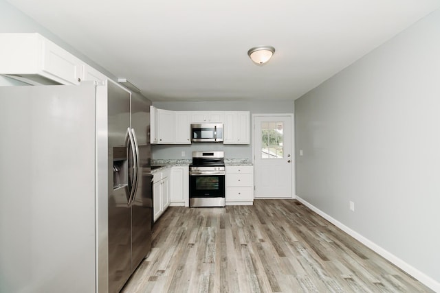 kitchen featuring light wood finished floors, appliances with stainless steel finishes, white cabinetry, and baseboards