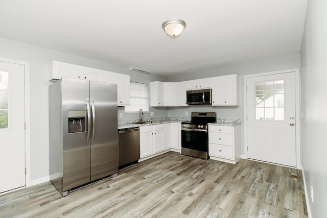 kitchen featuring a sink, appliances with stainless steel finishes, light wood-style flooring, and white cabinetry