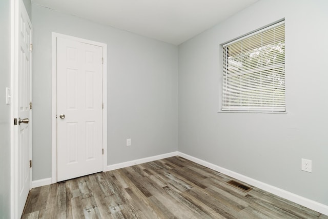 spare room with visible vents, baseboards, and wood finished floors