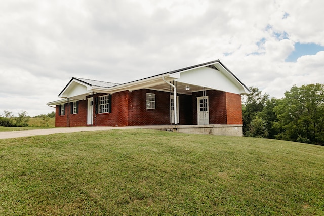 ranch-style house with covered porch, metal roof, brick siding, and a front yard