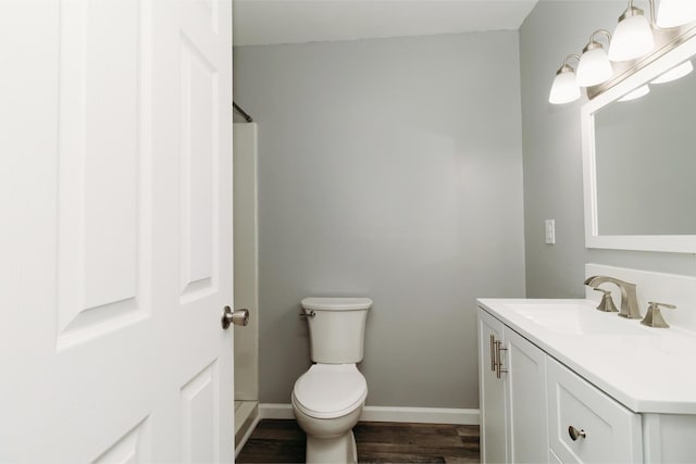 bathroom featuring toilet, wood finished floors, vanity, and baseboards