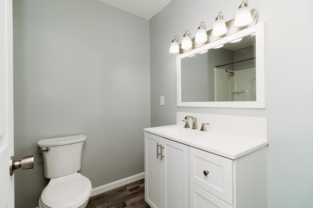 bathroom featuring toilet, baseboards, wood finished floors, and vanity