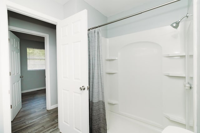 full bath featuring a shower with curtain, baseboards, and wood finished floors