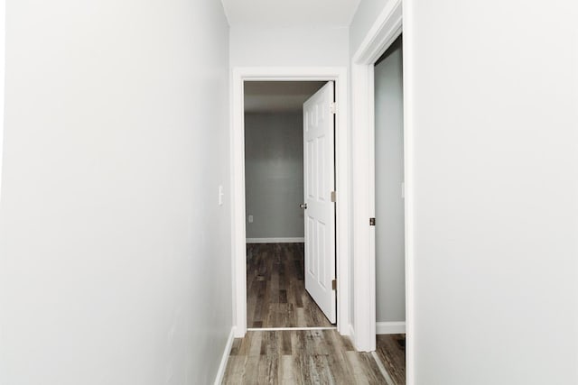 hall with baseboards and wood finished floors