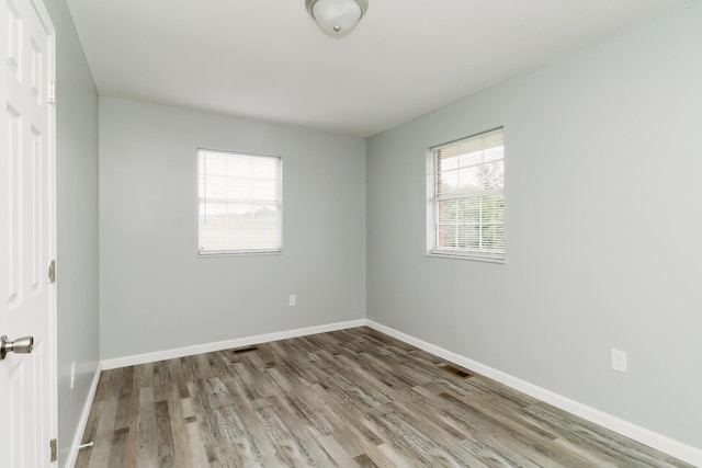 empty room with visible vents, baseboards, and wood finished floors