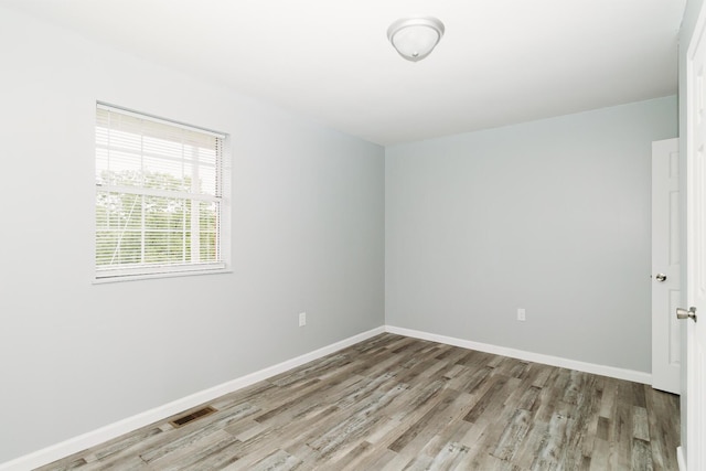 unfurnished room featuring light wood-style flooring, visible vents, and baseboards