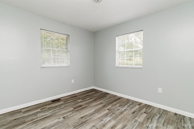 empty room featuring visible vents, baseboards, and wood finished floors