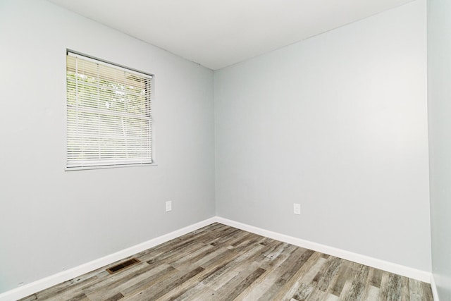 unfurnished room featuring baseboards, visible vents, and wood finished floors