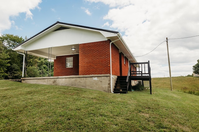 view of home's exterior featuring brick siding, a lawn, and stairs