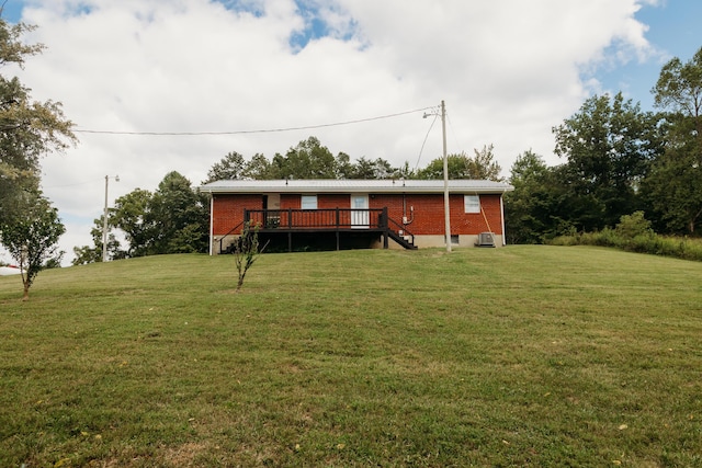 rear view of property featuring a yard, metal roof, a deck, and brick siding