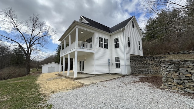 view of front of home with a balcony, a patio area, a detached garage, and an outdoor structure