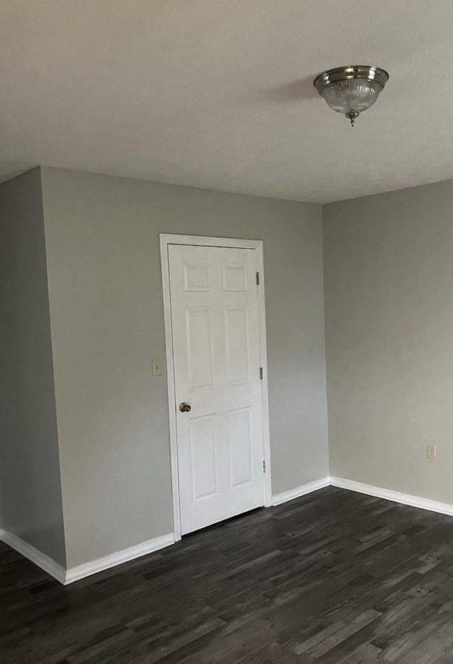 empty room featuring dark wood-type flooring and baseboards