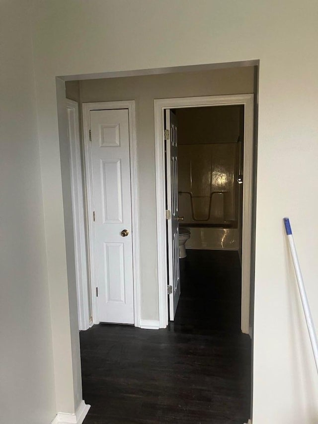 hallway featuring dark wood finished floors and baseboards