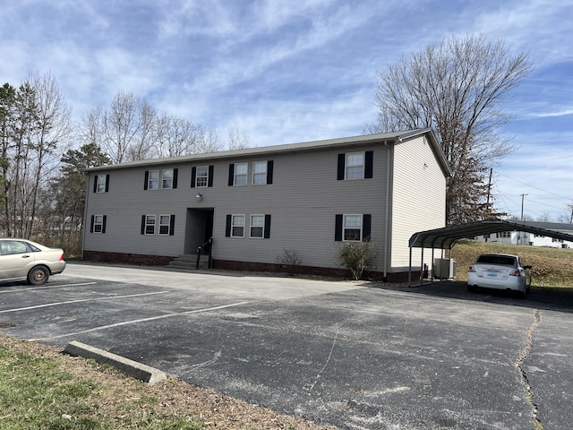 view of building exterior with uncovered parking and central AC unit