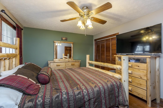 bedroom with a ceiling fan, a textured ceiling, and wood finished floors