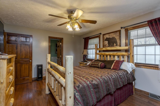 bedroom with a textured ceiling, wood finished floors, a ceiling fan, visible vents, and baseboards